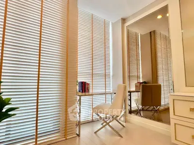 Elegant study room with modern chair, desk, and large mirror reflecting natural light through blinds.