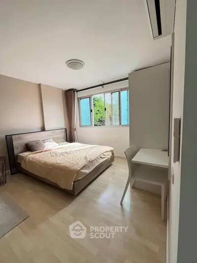 Spacious bedroom with large window and modern furnishings in a cozy apartment.