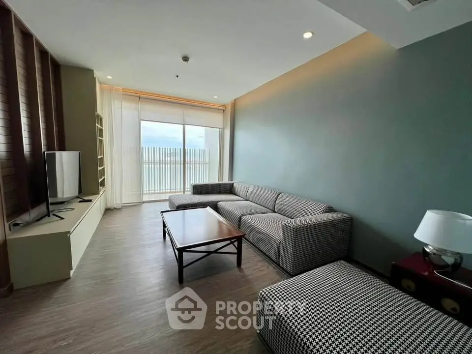 Spacious modern living room with large windows and stylish furniture, offering a serene ambiance and natural light.