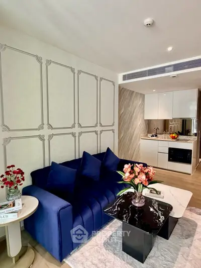 Modern living room with stylish blue sofa and compact kitchen area