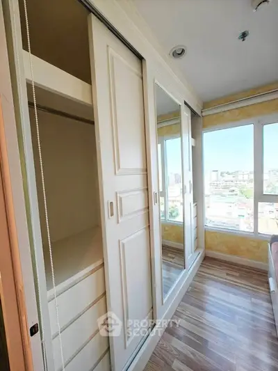 Spacious bedroom with large mirrored wardrobe and city view