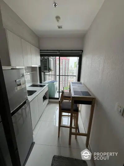 Modern compact kitchen with city view, featuring sleek appliances and a cozy dining area.