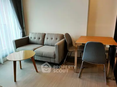 Modern living room with stylish sofa, glass coffee table, and dining set in a bright apartment.