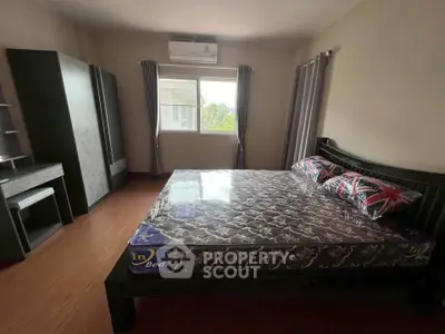 Spacious bedroom with large window and modern furnishings.