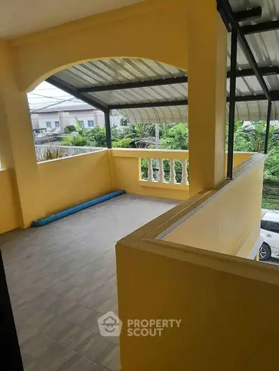 Spacious balcony with covered roof and garden view in suburban home.