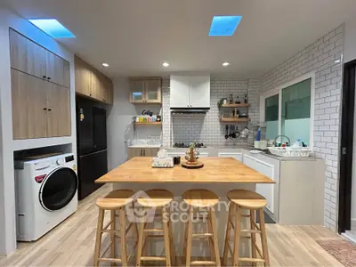 Modern kitchen with island, gas stove, and washing machine in stylish open layout.