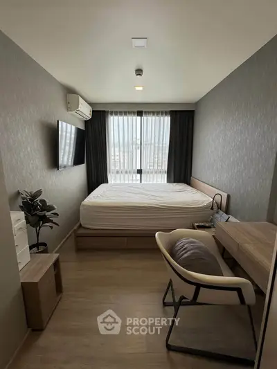 Modern bedroom with sleek furniture and large window offering natural light.