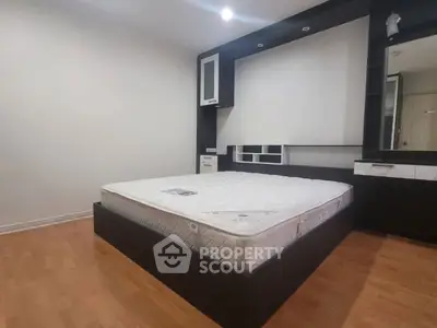 Spacious bedroom with modern design and hardwood flooring, featuring a stylish bed frame and built-in storage.