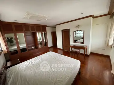 Spacious bedroom with wooden flooring and built-in wardrobe in a modern apartment.