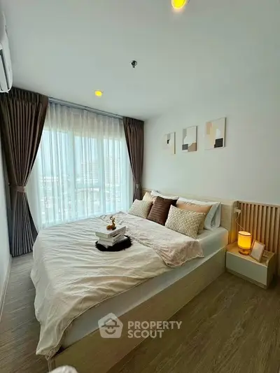 Modern bedroom with large window and stylish decor in a high-rise apartment.