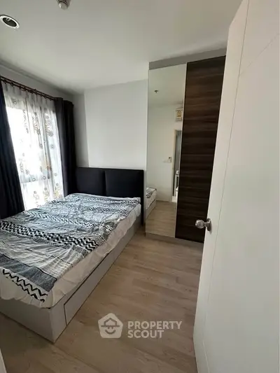 Modern bedroom with stylish decor and ample natural light, featuring a comfortable bed and sleek wooden flooring.