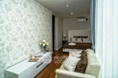 Luxurious bedroom with elegant decor and cozy seating area, featuring floral wallpaper and hardwood floors.