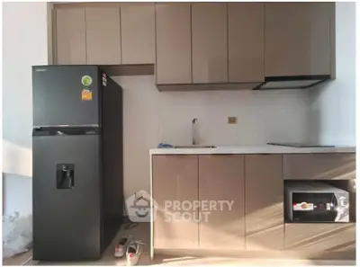 Modern kitchen with sleek cabinetry, black fridge, and built-in microwave, perfect for contemporary living.