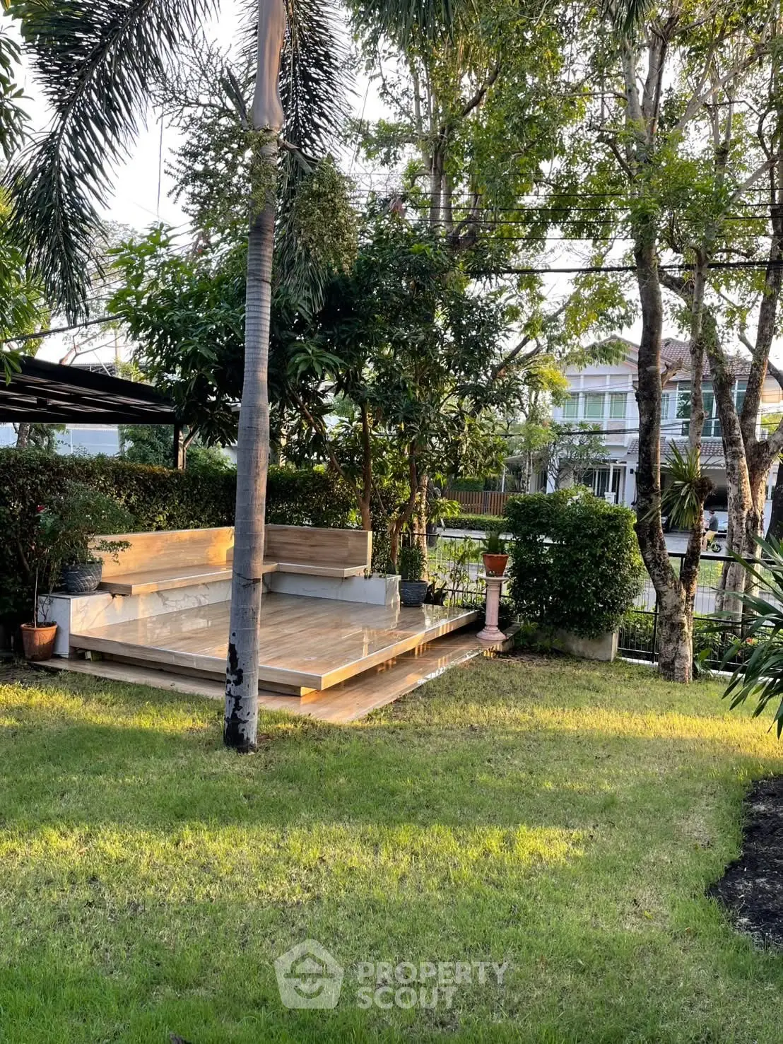 Charming garden with lush greenery and cozy seating area in serene residential setting.