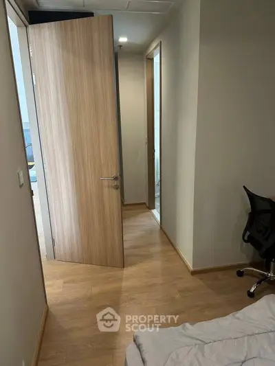 Modern apartment hallway with wooden flooring and open door to bedroom