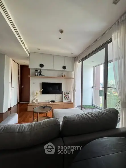 Modern living room with balcony view, featuring sleek furniture and abundant natural light.