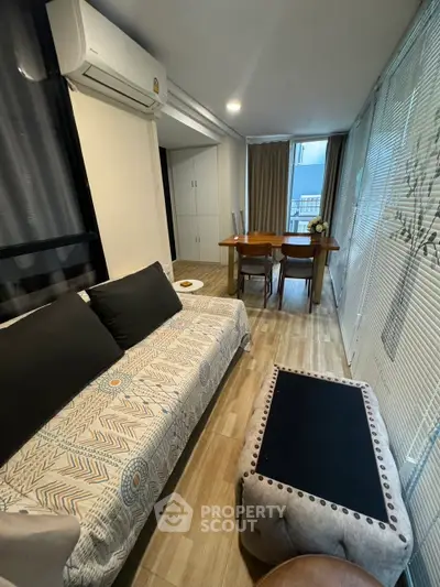 Cozy living room with modern decor and dining area, featuring natural light and stylish furnishings.