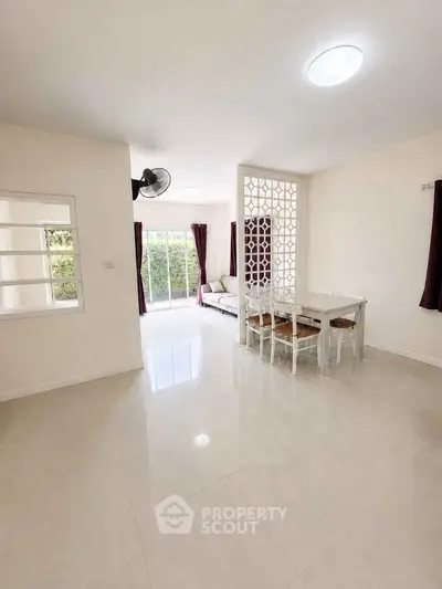 Spacious living room with modern decor and natural light, featuring a dining area and stylish partition.