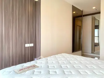Modern bedroom with stylish wood paneling and mirrored wardrobe, featuring a comfortable mattress.