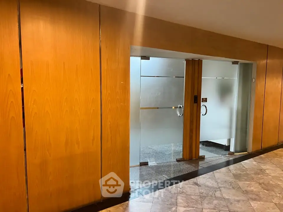 Elegant building entrance with modern glass doors and wooden paneling.