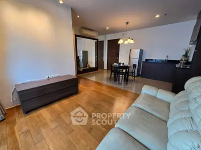 Spacious open-layout living room with wooden flooring and modern kitchen area.