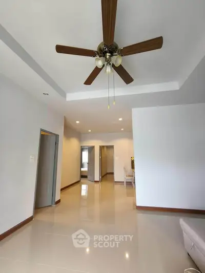 Spacious living room with ceiling fan and glossy tiled floor in modern apartment.