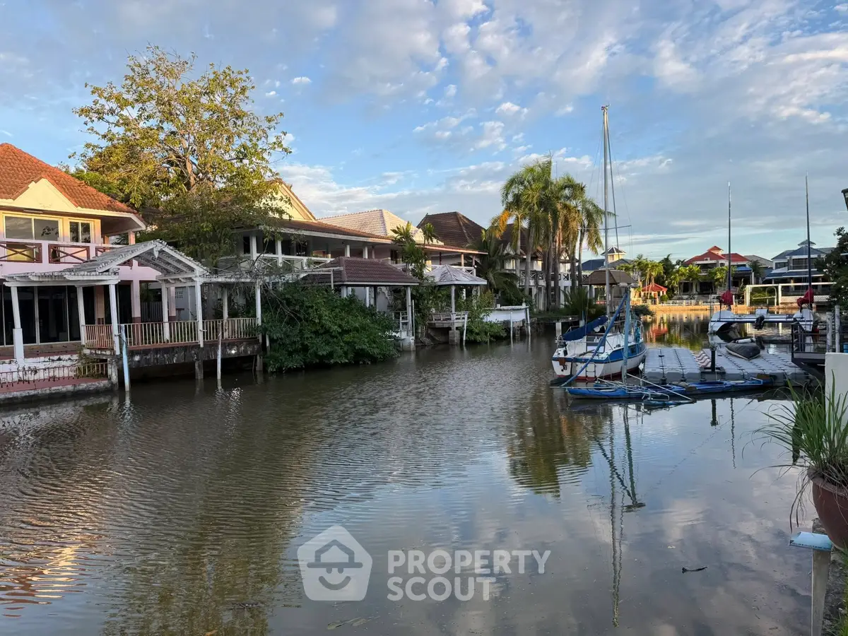 Scenic waterfront homes with private docks and lush greenery under a blue sky.