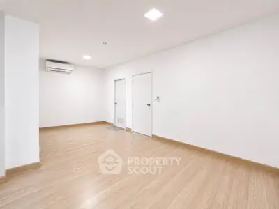 Spacious empty room with wooden flooring and white walls, ideal for customization.
