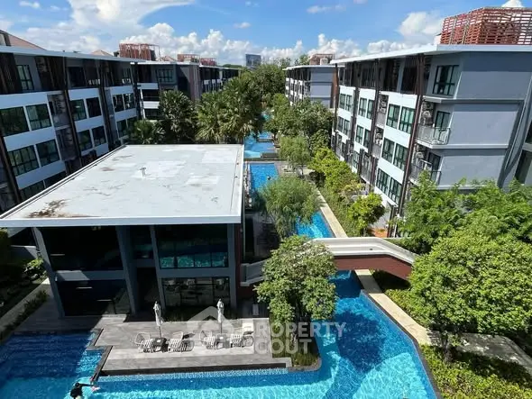 Luxurious apartment complex with stunning pool and lush greenery, offering a serene and modern living environment.