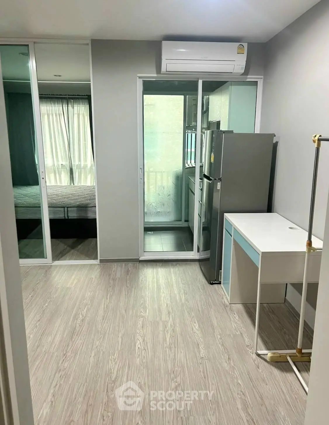 Modern apartment interior with sleek flooring, air conditioning, and a compact kitchen area.