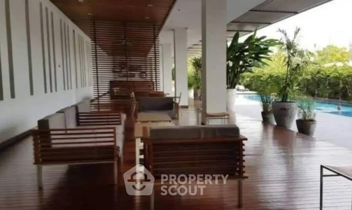 Luxurious poolside lounge area with modern wooden seating and lush greenery.