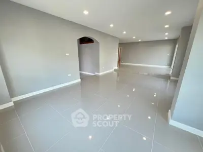 Spacious modern living room with glossy tiled floors and recessed lighting