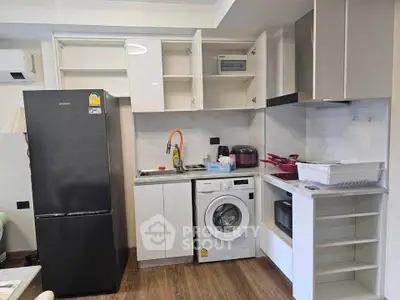 Modern kitchen with washing machine, fridge, and microwave in compact layout.