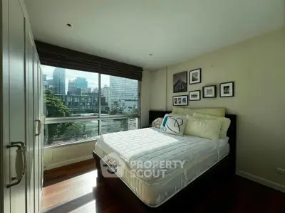 Bright bedroom with city view, large window, and stylish decor in modern apartment.