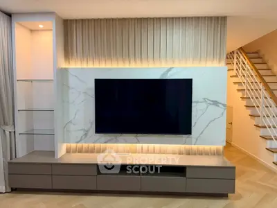 Modern living room with stylish TV unit and elegant staircase