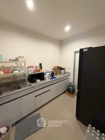 Modern kitchen with sleek cabinetry and spacious countertops, featuring a large refrigerator and ample storage space.