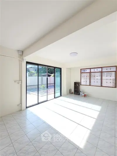 Spacious sunlit living room with large windows and tiled flooring