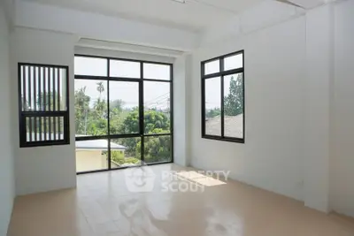 Spacious room with large windows offering a serene view of greenery, perfect for natural light lovers.