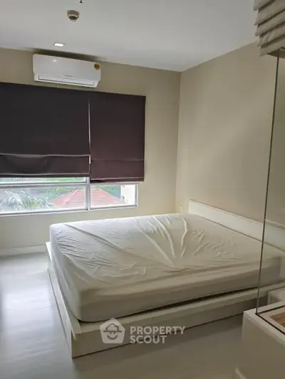 Spacious bedroom with large window and air conditioning in modern apartment.