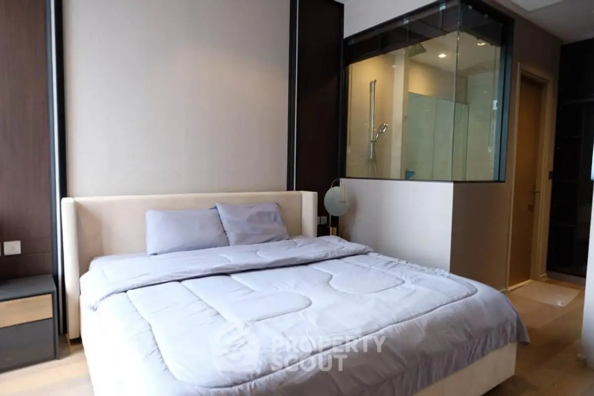 Modern bedroom with glass-walled ensuite bathroom and cozy decor