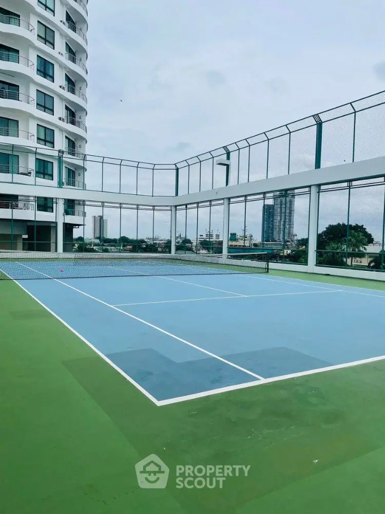 Modern apartment complex with rooftop tennis court and city views.