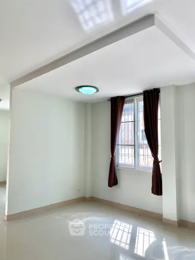 Spacious unfurnished room with large window and modern lighting