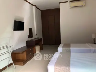 Spacious bedroom with twin beds, modern TV, and elegant wooden furniture.