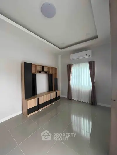 Spacious living room with modern entertainment unit and air conditioning, perfect for relaxation.