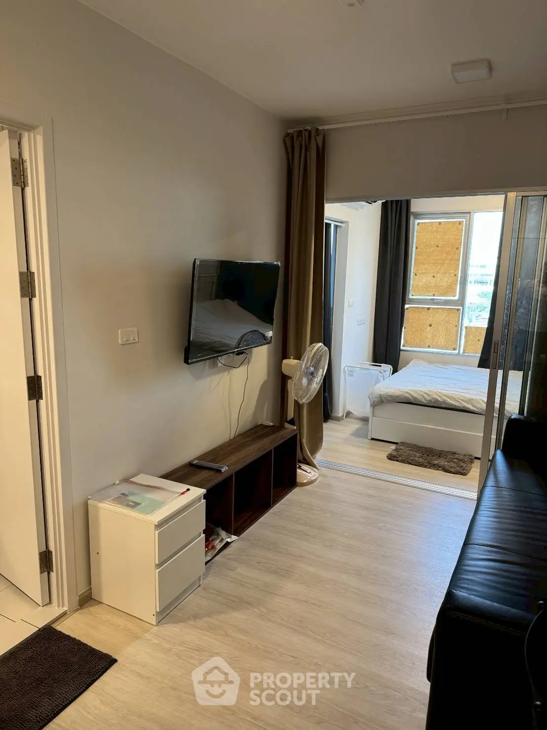 Modern apartment interior with open living room and bedroom layout, featuring sleek furniture and natural light.