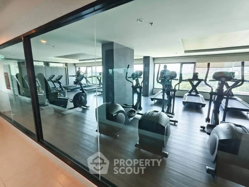 Modern gym with state-of-the-art equipment and panoramic city views in luxury residential building.
