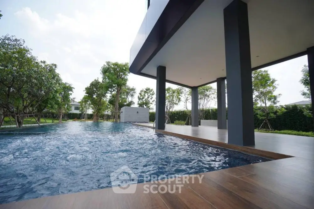 Luxurious modern poolside area with lush greenery and sleek architecture.