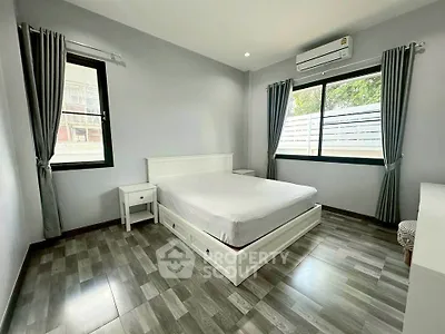 Spacious bedroom with modern decor and large windows for natural light.