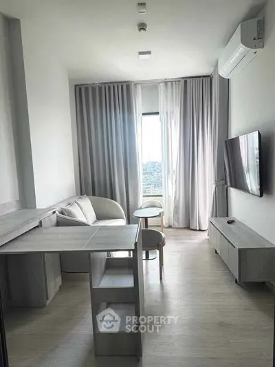 Modern living room with sleek furniture and large window offering natural light.