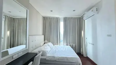 Modern bedroom with city view, featuring elegant decor and natural light.